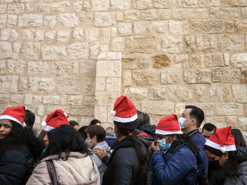 Heiligabend im vergangenen Jahr: Touristen - einige mit Weihnachtsmützen - stehen in Bethlehem vor der Geburtskirche Schlange. - Foto: Maya Alleruzzo/AP/dpa