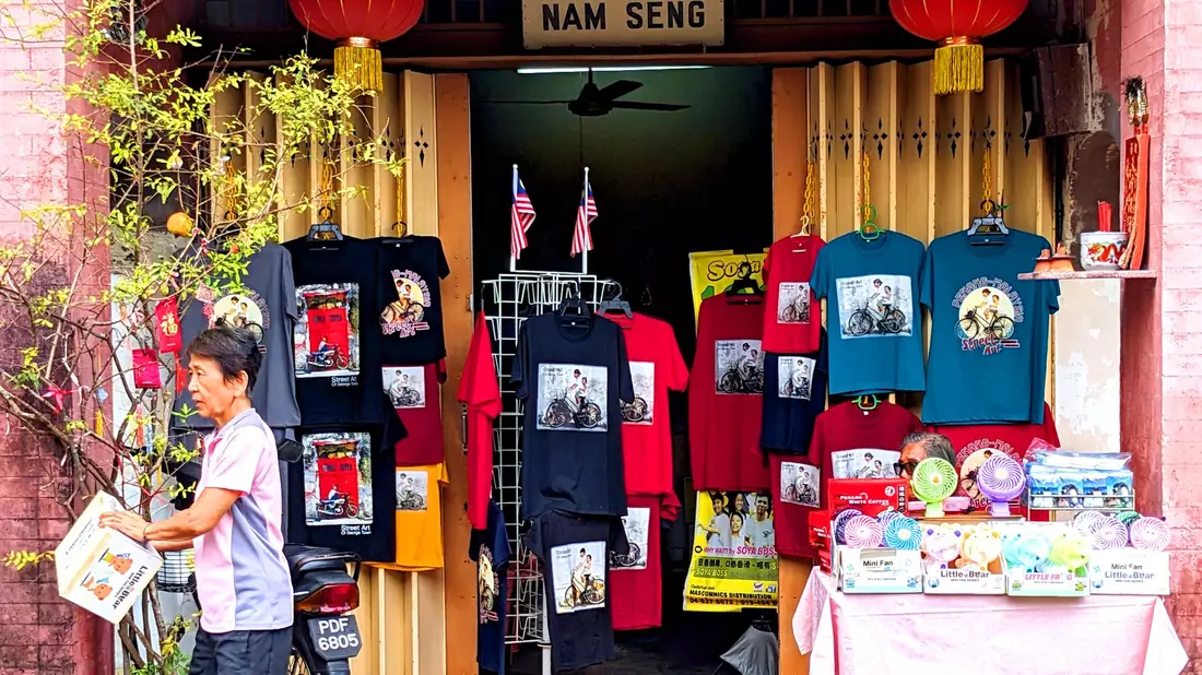 T-Shirts und andere Dinge, auf denen Street Art-Kunstwerke aus Penang abgebildet sind, werden in einem Geschäft zum Kauf angeboten. - Bild: Genevieve Tan Shu Thung/dpa