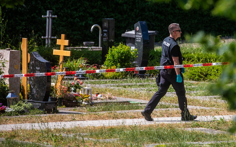 Ein Polizist geht über den abgesperrten Teil an einem Tatort auf einem Friedhof. - Foto: Christoph Schmidt/dpa