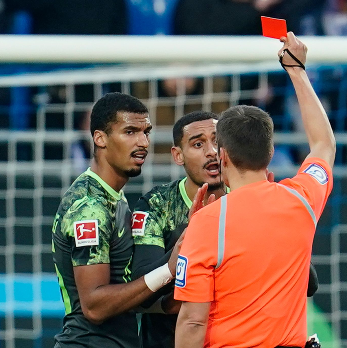 Schiedsrichter Robert Hartmann (r) zeigt Wolfsburgs Maxence Lacroix (M) in der 
27. Minute die rote Karte. - Foto: Uwe Anspach/dpa