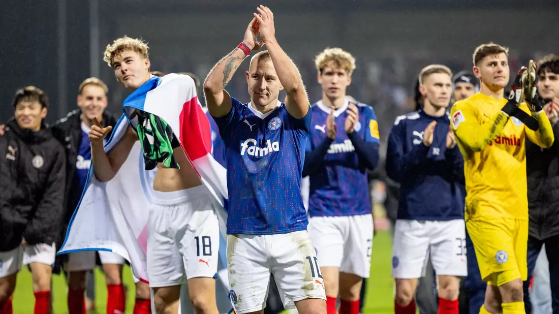 Die Kieler Spieler feierten mit den Anhängern, die nach dem Schlusspfiff auf das Spielfeld gestürmt waren. - Bild: Axel Heimken/dpa