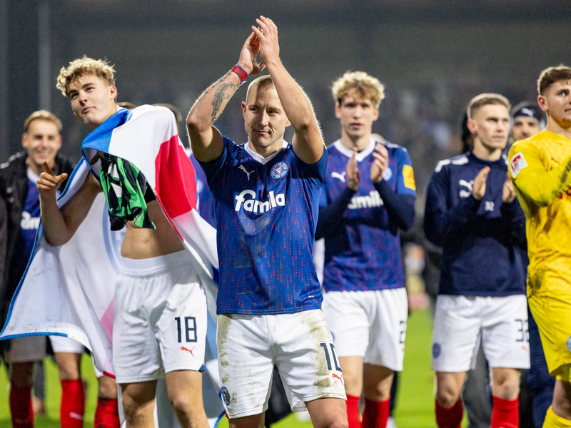 Die Kieler Spieler feierten mit den Anhängern, die nach dem Schlusspfiff auf das Spielfeld gestürmt waren. - Foto: Axel Heimken/dpa