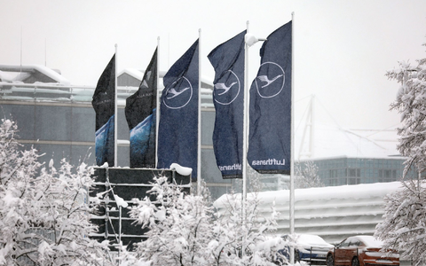 Fahnen der Lufthansa wehen am  Flughafen München im Schneetreiben. Die deutsche Fluggesellschaft kauft neue Maschinen ein. - Foto: Karl-Josef Hildenbrand/dpa