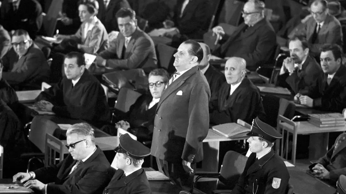 Der erste Auschwitz-Prozess im Plenarsaal der Frankfurter Stadtverordnetenversammlung wird eröffnet. In der ersten Reihe sitzt der Angeklagte Victor Capesius (mit dunkler Brille), hinter ihm steht der Angeklagte Oswald Kaduk. (zu dpa: «Als die Täter von Auschwitz in Frankfurt vor Gericht kamen») - Bild: Roland Witschel/dpa
