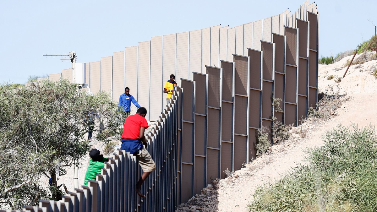 Migranten klettern über einen Zaun auf der Insel Lampedusa. - Foto: Cecilia Fabiano/LaPresse via ZUMA Press/dpa