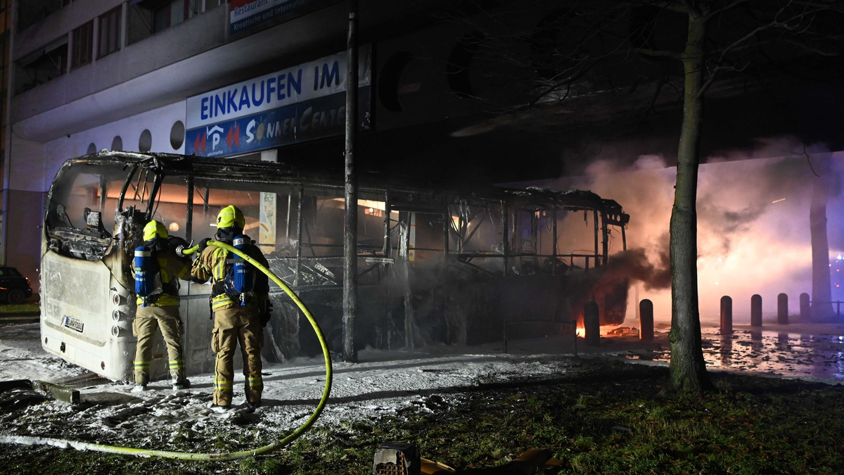 Einsatzkräfte der Feuerwehr löschen in der Silvesternacht 2022/2023 im Bezirk Berlin-Neukölln einen brennenden Bus, der von Unbekannten angezündet worden war. - Foto: Paul Zinken/dpa