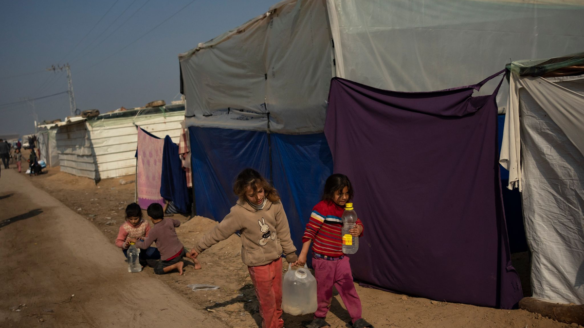 Palästinensische Kinder tragen Wasser in einem behelfsmäßigen Zeltlager. - Foto: Fatima Shbair/AP/dpa