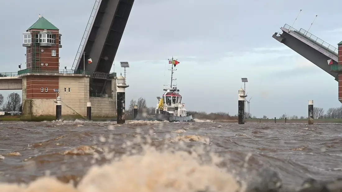 Ein Schlepper fährt bei schlechtem Wetter über die Ems. - Bild: Lars Penning/dpa