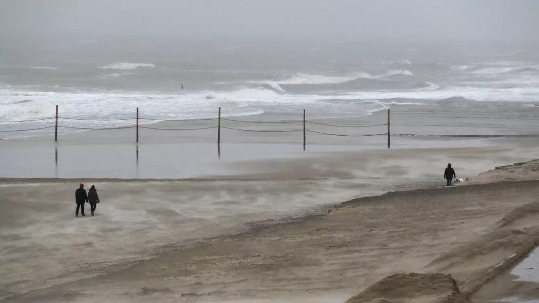 Strandspaziergänger trotzen dem starken Wind auf der Insel Wangerooge. - Bild: Peter Kuchenbuch-Hanken/-/dpa