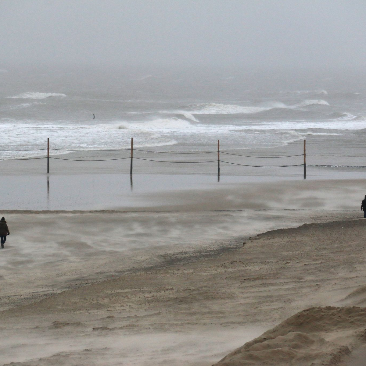 Strandspaziergänger trotzen dem starken Wind auf der Insel Wangerooge. - Foto: Peter Kuchenbuch-Hanken/-/dpa