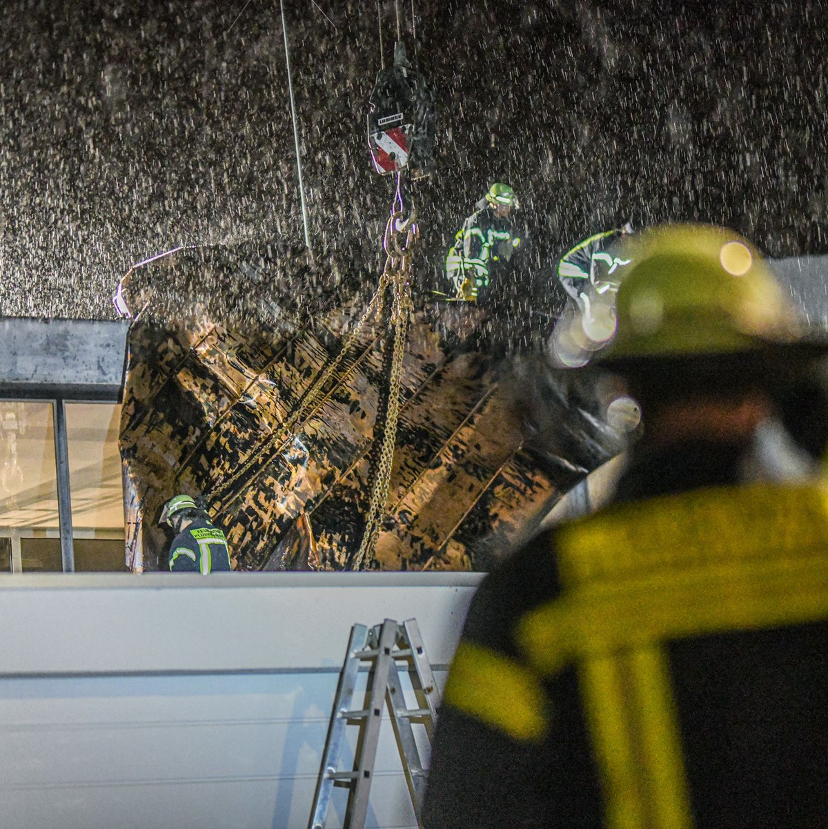 Einsatzkräfte der Feuerwehr sichern in Plüderhausen bei Stuttgart ein Teil des Daches ihres Feuerwehrhauses mit einem Kran. Zuvor hatte Sturntief «Zoltan» Teile des Daches abgedeckt. - Foto: Jason Tschepljakow/dpa