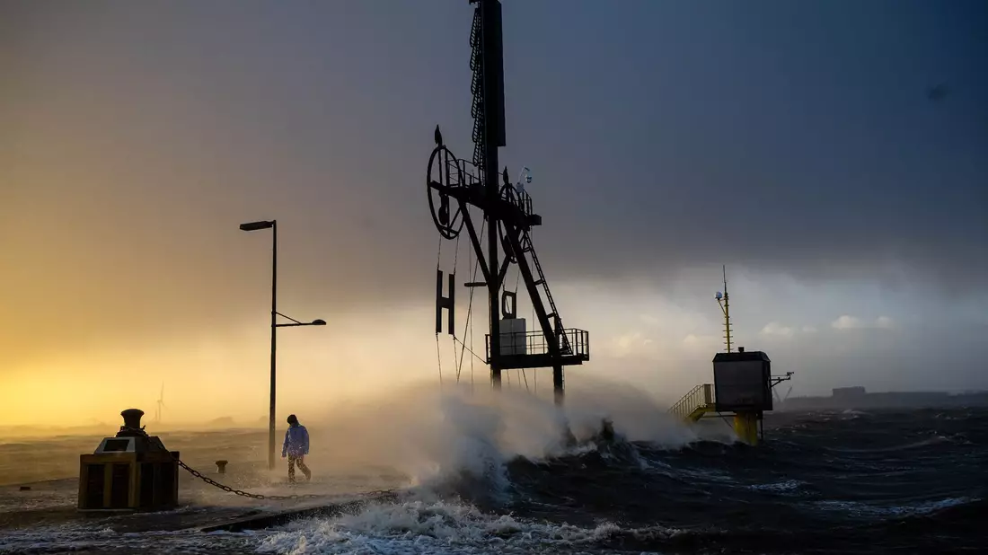 Ein Spaziergänger läuft bei Sturmflut und Wellen am Ufer der Wesermündung in Bremerhaven entlang. - Bild: Sina Schuldt/dpa