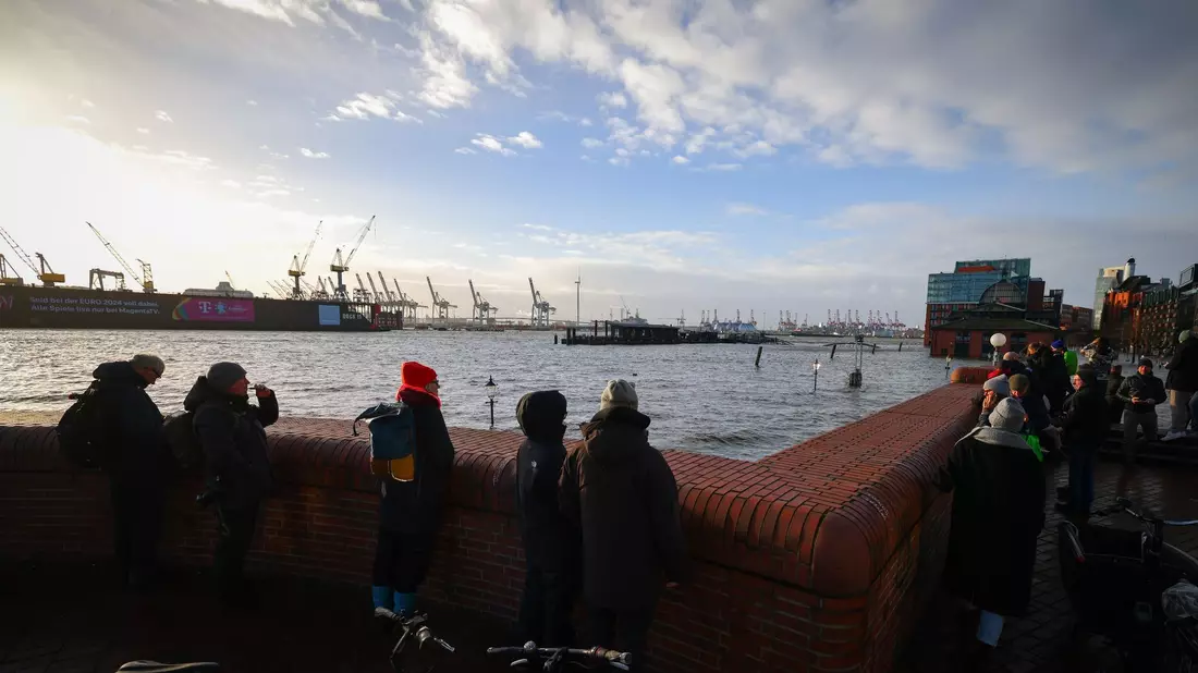 Schaulustige beobachten von einer Promenade am Hamburger Fischmarkt die Überflutung durch die Sturmflut. - Bild: Christian Charisius/dpa