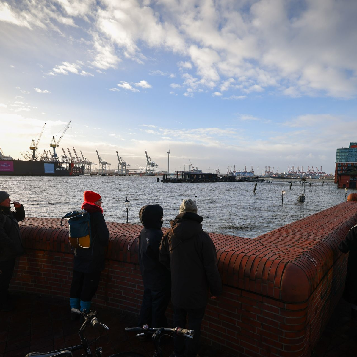 Schaulustige beobachten von einer Promenade am Hamburger Fischmarkt die Überflutung durch die Sturmflut. - Foto: Christian Charisius/dpa