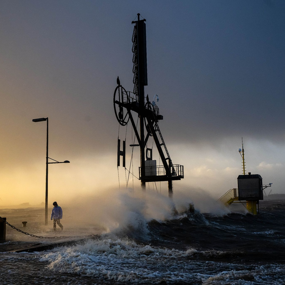 Ein Spaziergänger läuft bei Sturmflut und Wellen am Ufer der Wesermündung in Bremerhaven entlang. - Foto: Sina Schuldt/dpa