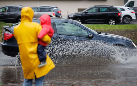 Eine Mutter und ihr Kind blicken auf eine teils überflutete Straße in Osnabrück. - Foto: Friso Gentsch/dpa Eine Mutter und ihr Kind blicken auf eine teils überflutete Straße in Osnabrück. - Foto: Friso Gentsch/dpa