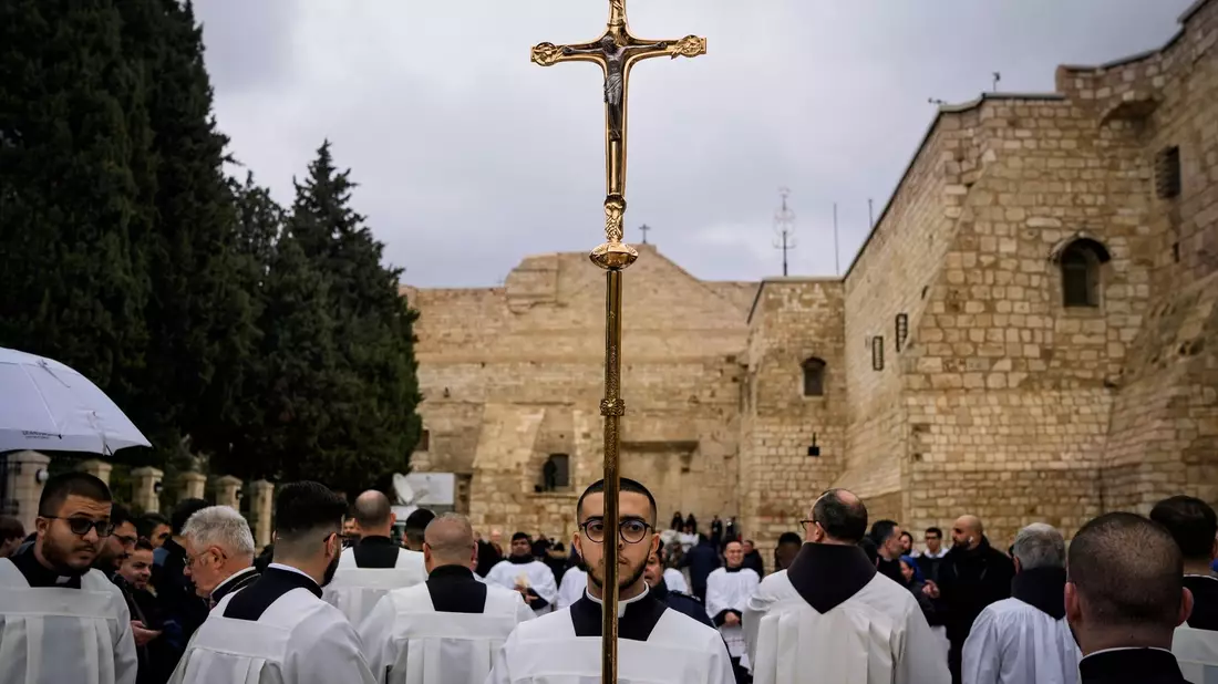 Katholische Geistliche gehen am Heiligabend in Bethlehem im Westjordanland in einer Prozession neben der Geburtskirche. - Bild: Leo Correa/AP/dpa