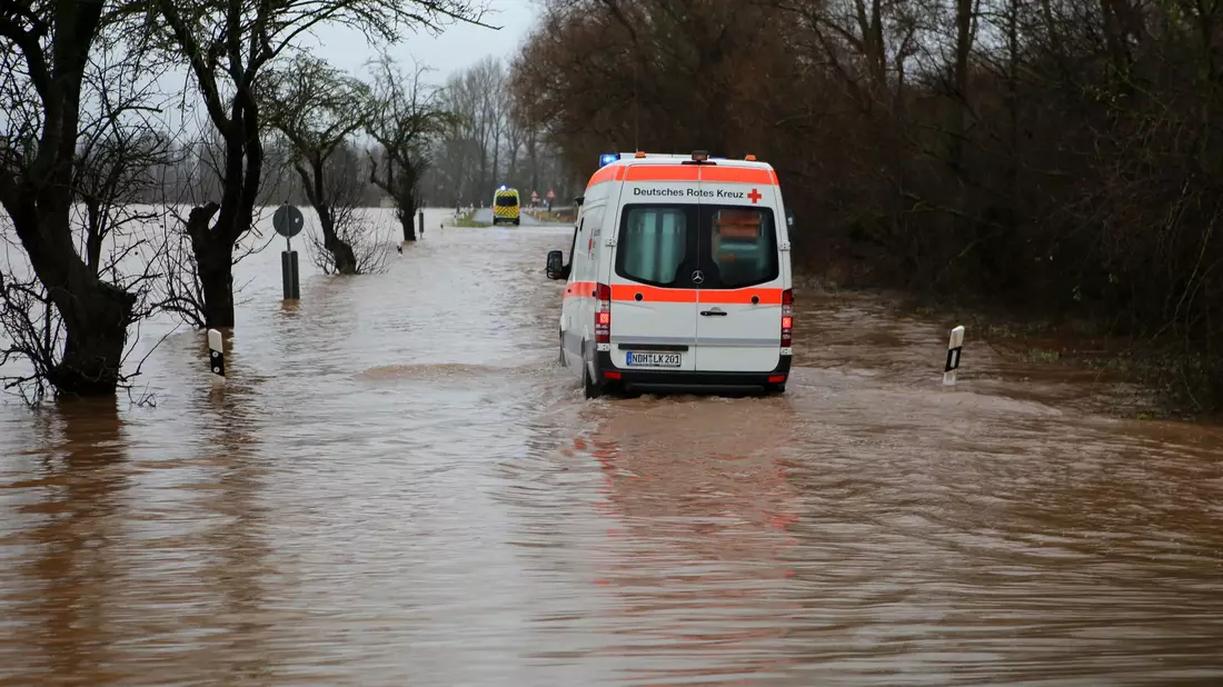 Ein Krankenwagen fährt über eine von Hochwasser überflutete Straße nach Windehausen in Thüringen. - Bild: Stefan Rampfel/dpa