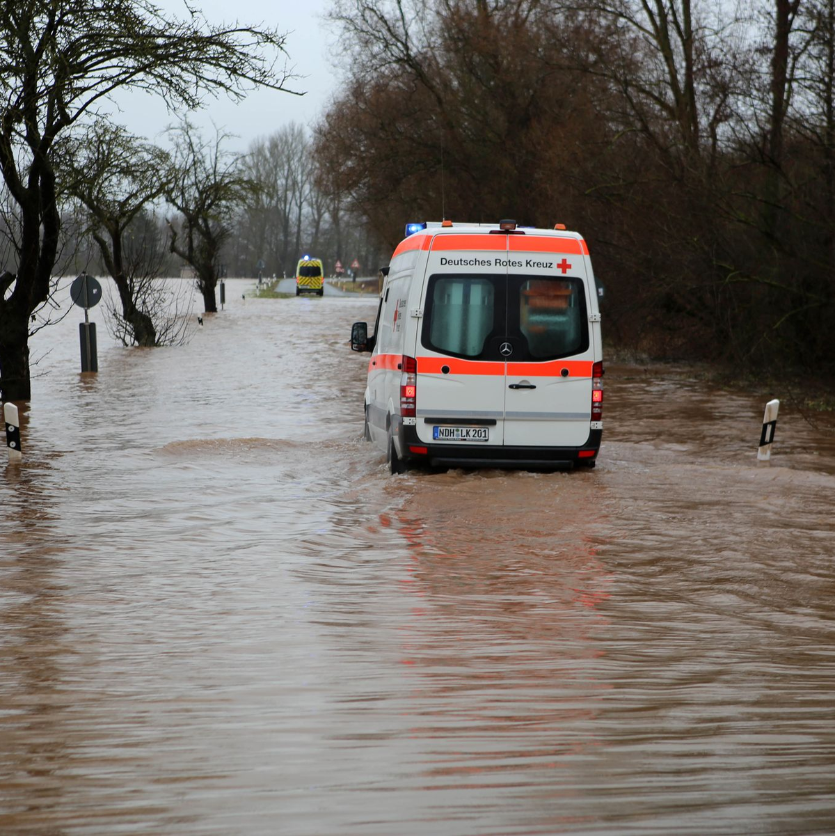 Ein Krankenwagen fährt über eine von Hochwasser überflutete Straße nach Windehausen in Thüringen. - Foto: Stefan Rampfel/dpa
