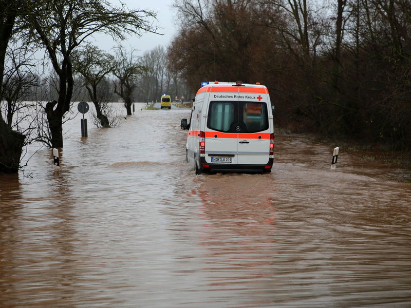 Ein Krankenwagen fährt über eine von Hochwasser überflutete Straße nach Windehausen in Thüringen. - Foto: Stefan Rampfel/dpa