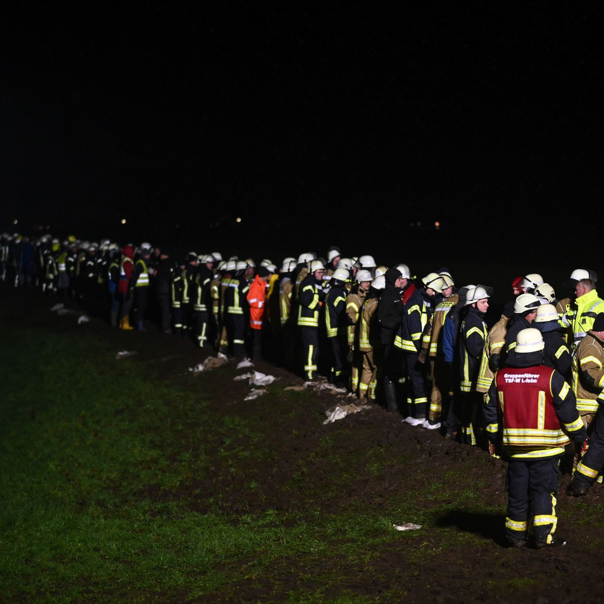Mit einer Menschenkette werden gefüllte Sandsäcke zu den Bruchstellen gebracht. - Foto: Lars Penning/dpa
