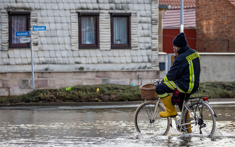 Ein Feuerwehrmann auf einem Fahrrad in einer überschwemmten Straße in Windehausen. - Foto: Christoph Reichwein/dpa Ein Feuerwehrmann auf einem Fahrrad in einer überschwemmten Straße in Windehausen. - Foto: Christoph Reichwein/dpa