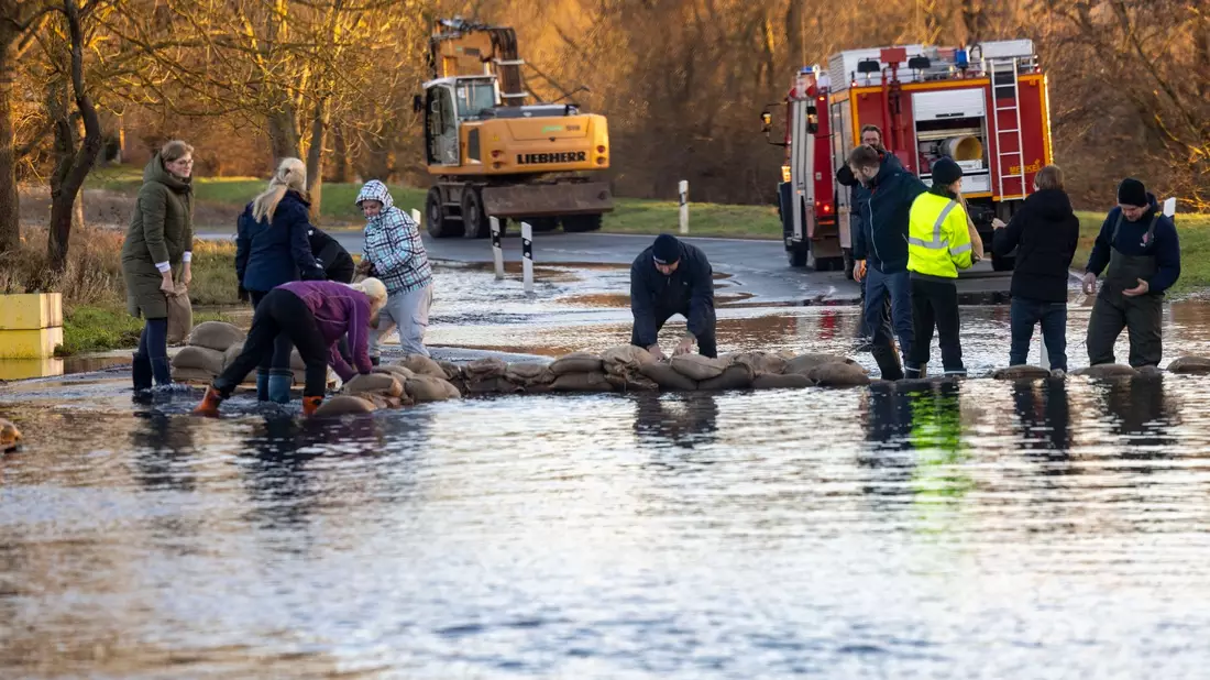 Helfer bauen mit Sandsäcken einen Deich auf einer Straße im thüringischen Windehausen. - Bild: Christoph Reichwein/dpa