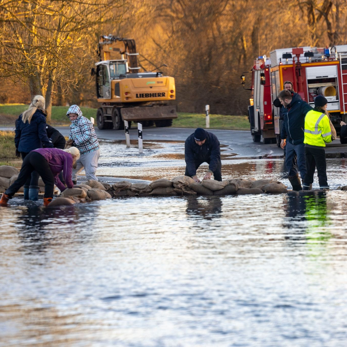 Helfer bauen mit Sandsäcken einen Deich auf einer Straße im thüringischen Windehausen. - Foto: Christoph Reichwein/dpa