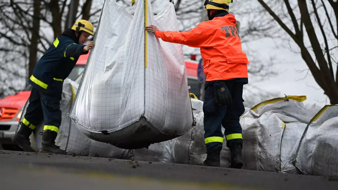 Ehrenamtliche Einsatzkräfte der Feuerwehr und des Technischen Hilfswerks (THW) bauen einen Mobildeich mit Sandsäcken auf, um ein Wohngebiet in Meppen unweit der Ems zu sichern. - Bild: Lars Penning/dpa