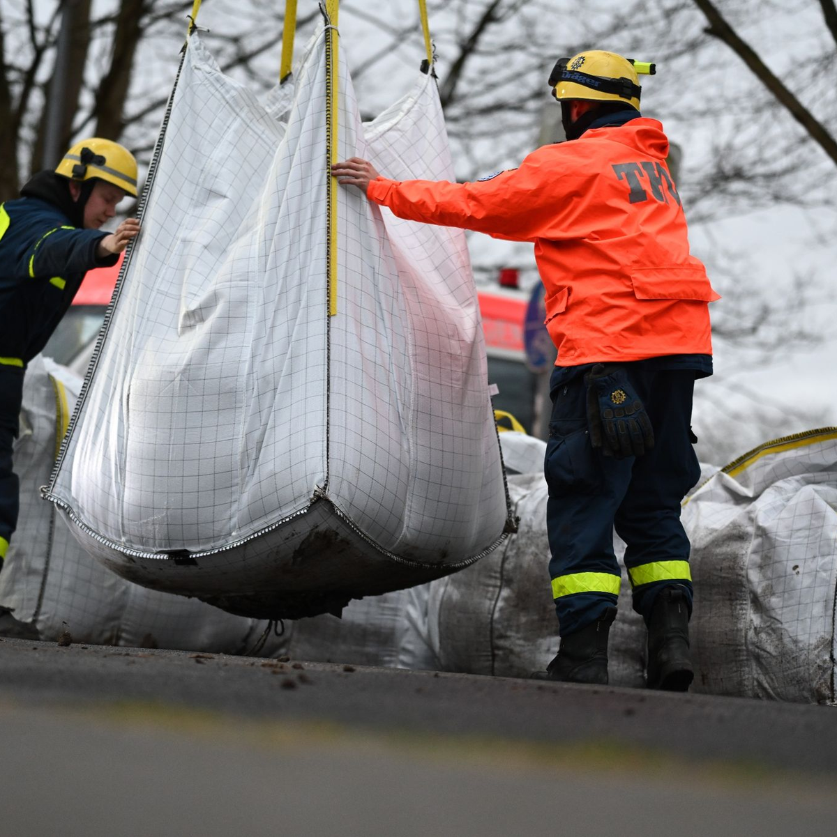Ehrenamtliche Einsatzkräfte der Feuerwehr und des Technischen Hilfswerks (THW) bauen einen Mobildeich mit Sandsäcken auf, um ein Wohngebiet in Meppen unweit der Ems zu sichern. - Foto: Lars Penning/dpa