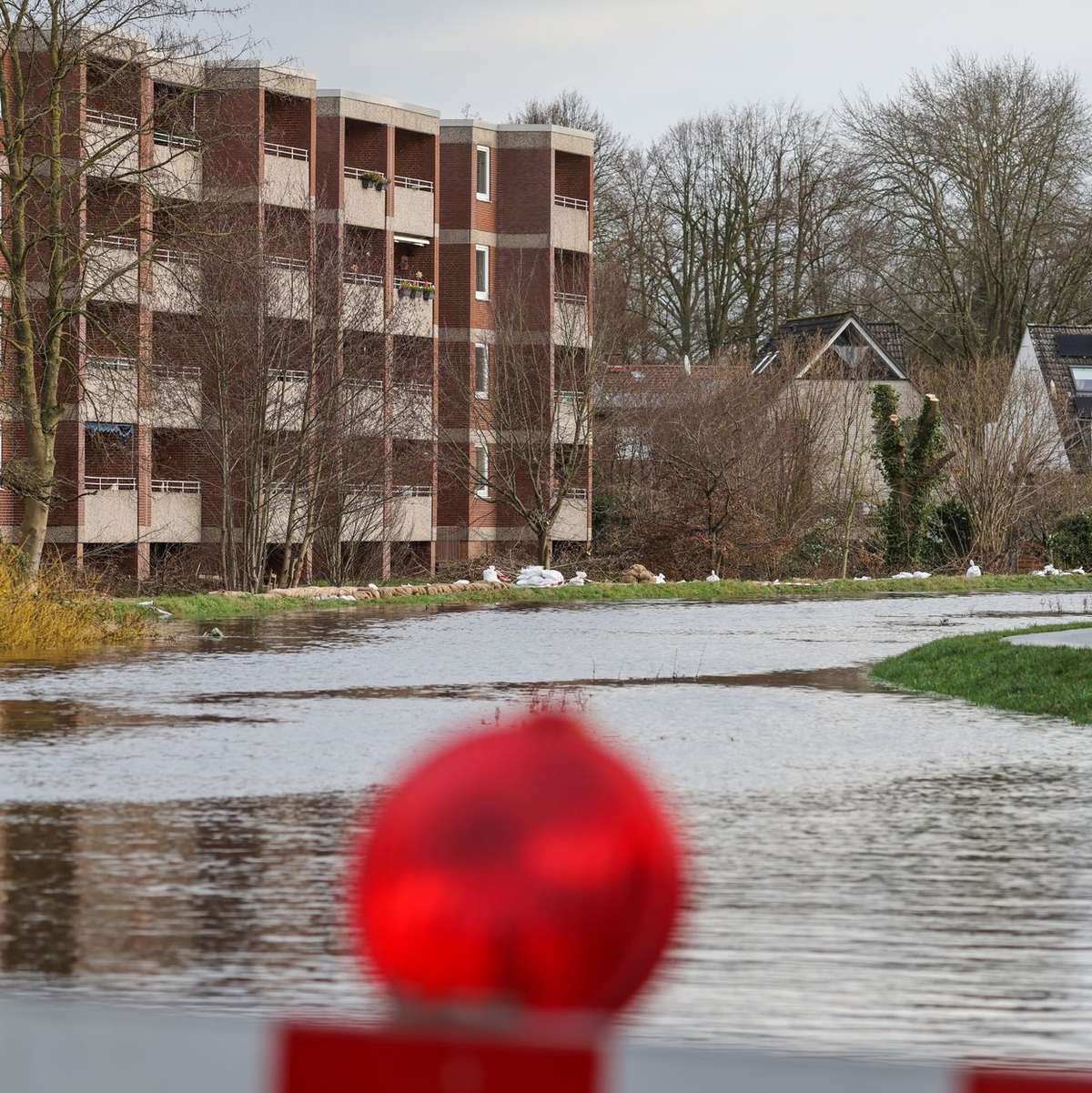 Sandsäcke liegen auf einem durchweichten Deich vor evakuierten Wohnhäusern in Lilienthal bei Bremen. - Foto: Focke Strangmann/dpa