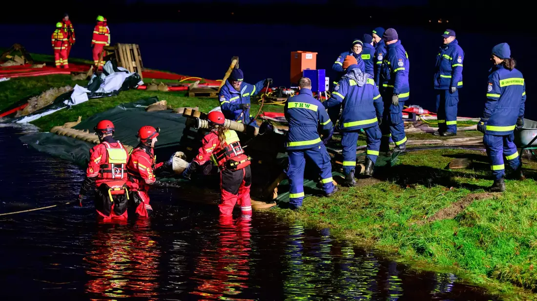 Ehrenamtliche Einsatzkräfte vom THW und der DLRG befestigen einen Deich in Niedersachsen. - Bild: Philipp Schulze/dpa