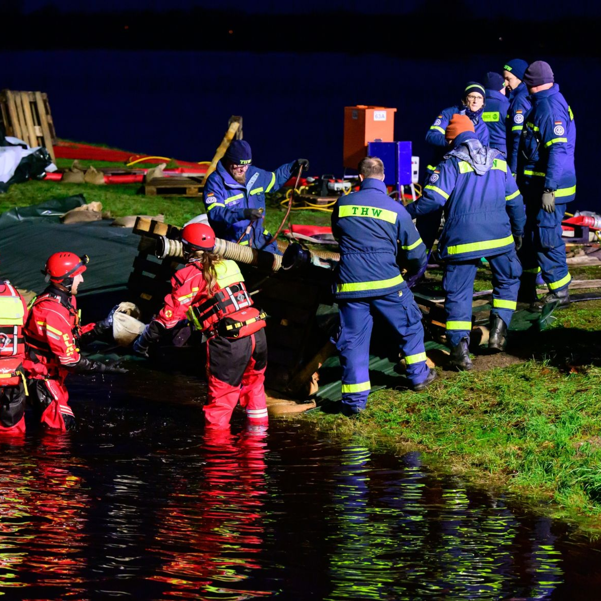 Ehrenamtliche Einsatzkräfte vom THW und der DLRG befestigen einen Deich in Niedersachsen. - Foto: Philipp Schulze/dpa