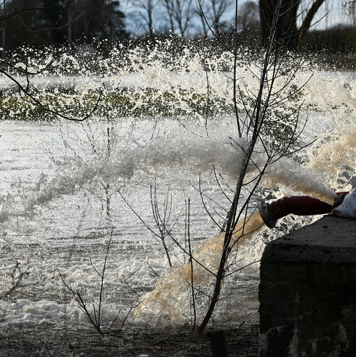 Die Feuerwehr pumpt Wasser, welches durch den Deich gesickert ist, zurück in den Fluß Helme. So soll eine Überflutung des Ortes Oberröblingen verhindert werden. - Foto: Heiko Rebsch/dpa