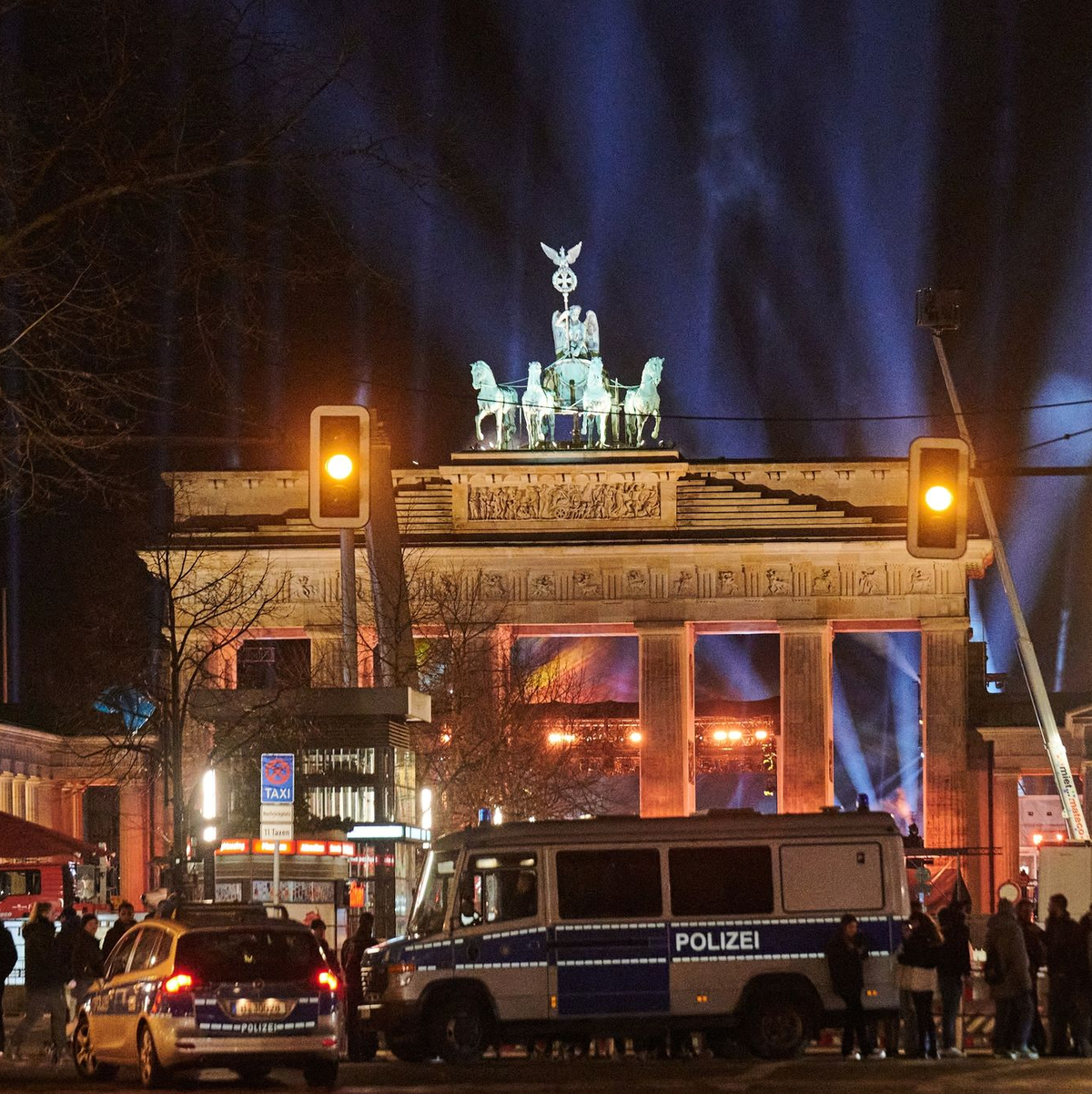Silvester in Berlin: Polizeiwagen stehen vorm angestrahlten Brandenburger Tor. - Foto: Annette Riedl/dpa