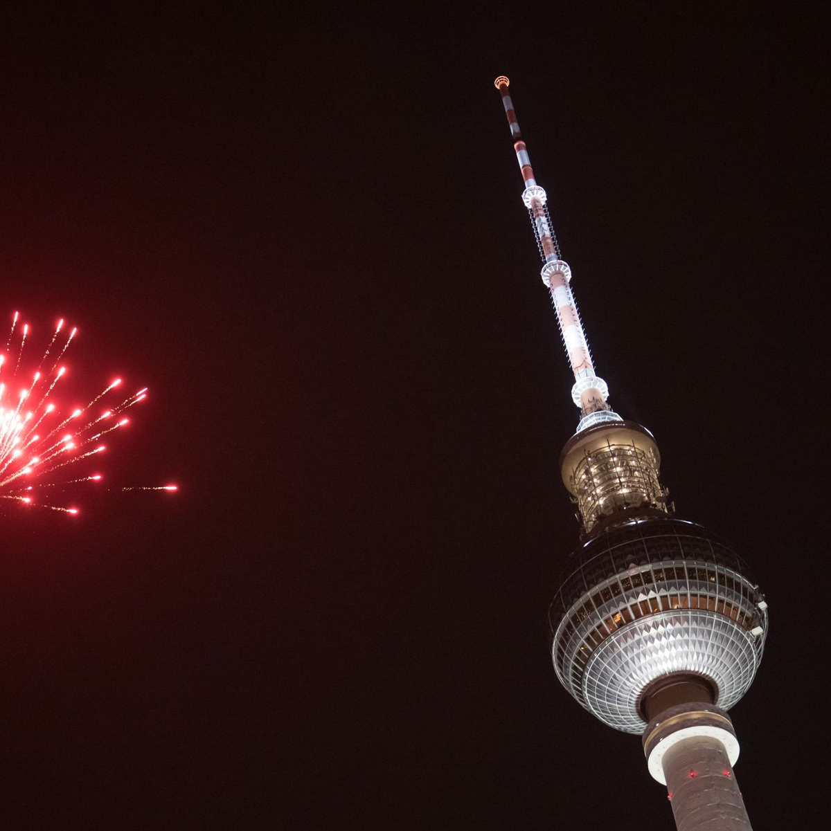 Eine Rakete explodiert in der Silvesternacht in der Nähe des Berliner Fernsehturms. - Foto: Sebastian Christoph Gollnow/dpa