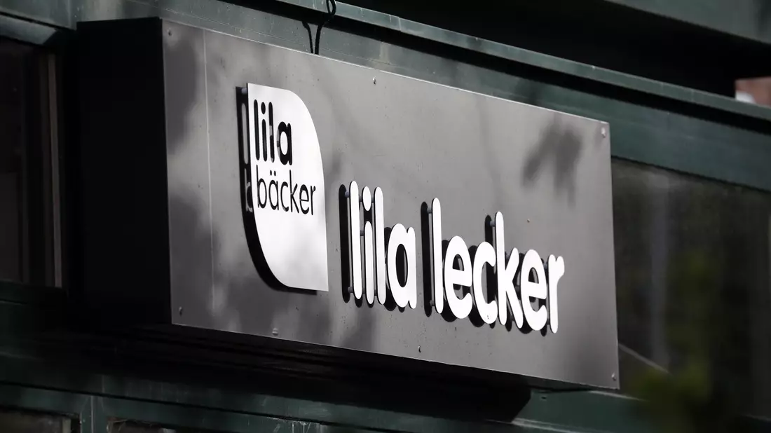 Das Logo des Unternehmens Lila Bäcker an einer Filiale in Warnemünde. - Bild: Bernd Wüstneck/dpa-Zentralbild/dpa