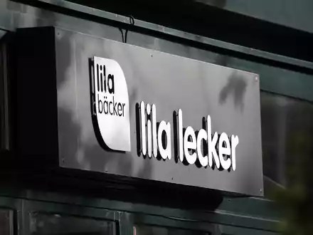 Das Logo des Unternehmens Lila Bäcker an einer Filiale in Warnemünde. - Foto: Bernd Wüstneck/dpa-Zentralbild/dpa