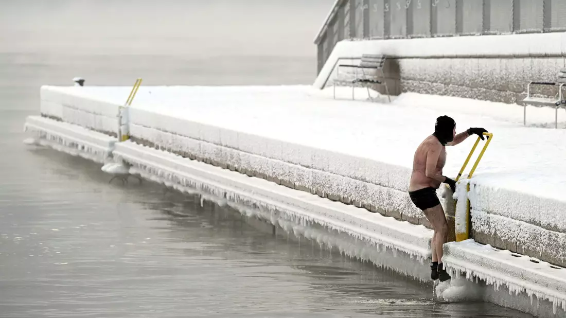 Ein Mann klettert in Helsinki aus dem eisigen Meer auf den Pier. - Bild: Vesa Moilanen/Lehtikuva/AP/dpa