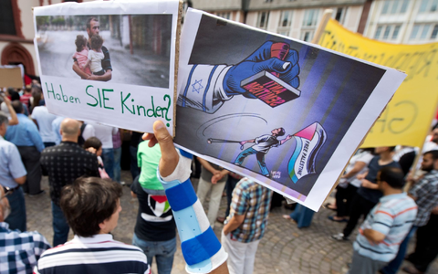 Ein Junge hält ein Plakat hoch, auf dem ein propalästinensischer Demonstrant unter einem Stempel mit der Aufschrift Anti Semitismus steht. - Foto: picture alliance / dpa Ein Junge hält ein Plakat hoch, auf dem ein propalästinensischer Demonstrant unter einem Stempel mit der Aufschrift Anti Semitismus steht. - Foto: picture alliance / dpa