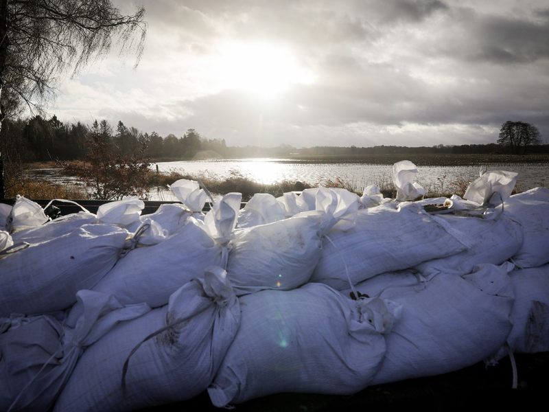 Sandsäcke an einer Landstraße am Ortseingang von Sandkrug bei Oldenburg. - Foto: Christian Charisius/dpa