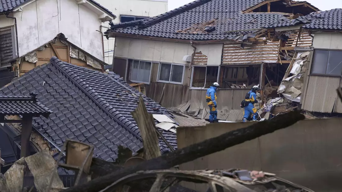 Einsatzkräfte der Polizei durchsuchen nach dem Erdbeben beschädigte Häuser in Wajima. - Bild: Uncredited/Kyodo News/AP