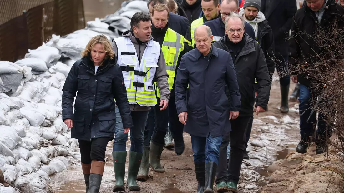 Bundeskanzler Olaf Scholz (vorne rechts) trägt bei seinem Besuch im Hochwassergebiet in Sangerhausen Gummistiefel. - Bild: Jan Woitas/dpa