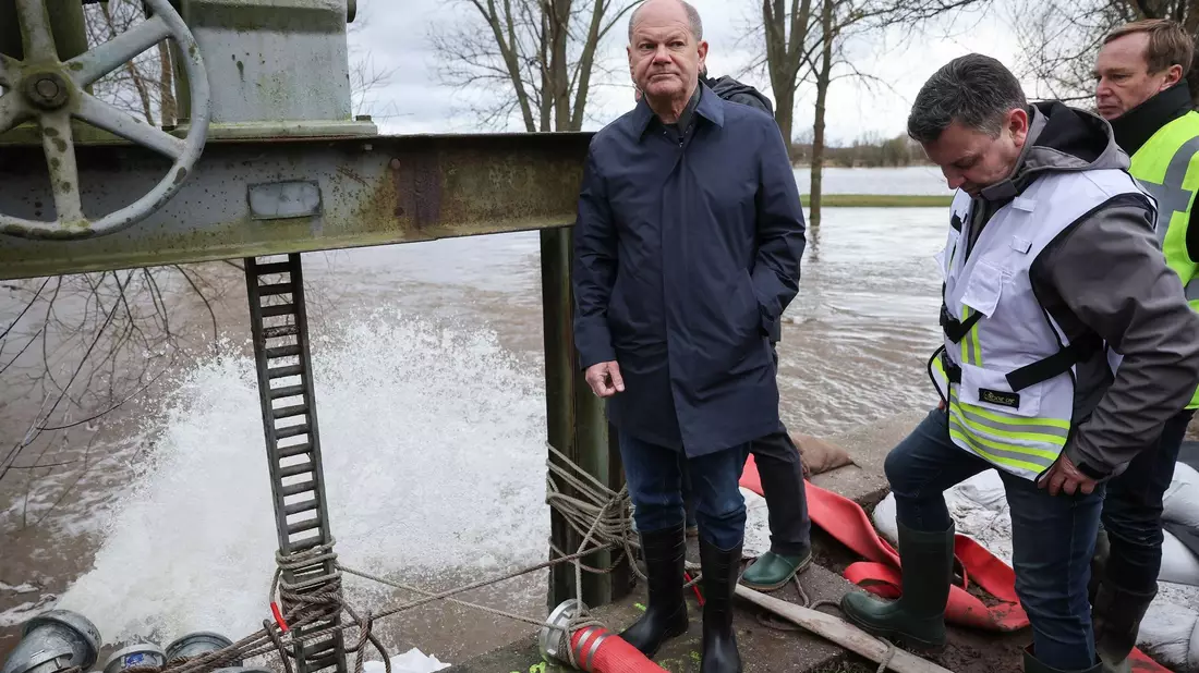 Bundeskanzler Olaf Scholz begutachtet ein Wehr in Sangerhausen. - Bild: Jan Woitas/dpa
