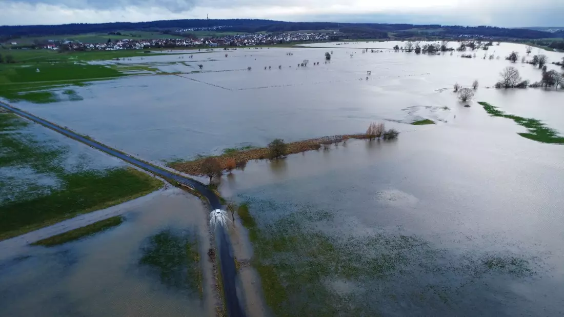 Ein Auto fährt am Rande des aufgestauten Rückhaltebeckens der Ohm. In Hessen ist noch keine Entspannung beim Hochwasser in Sicht. - Bild: Nadine Weigel/dpa