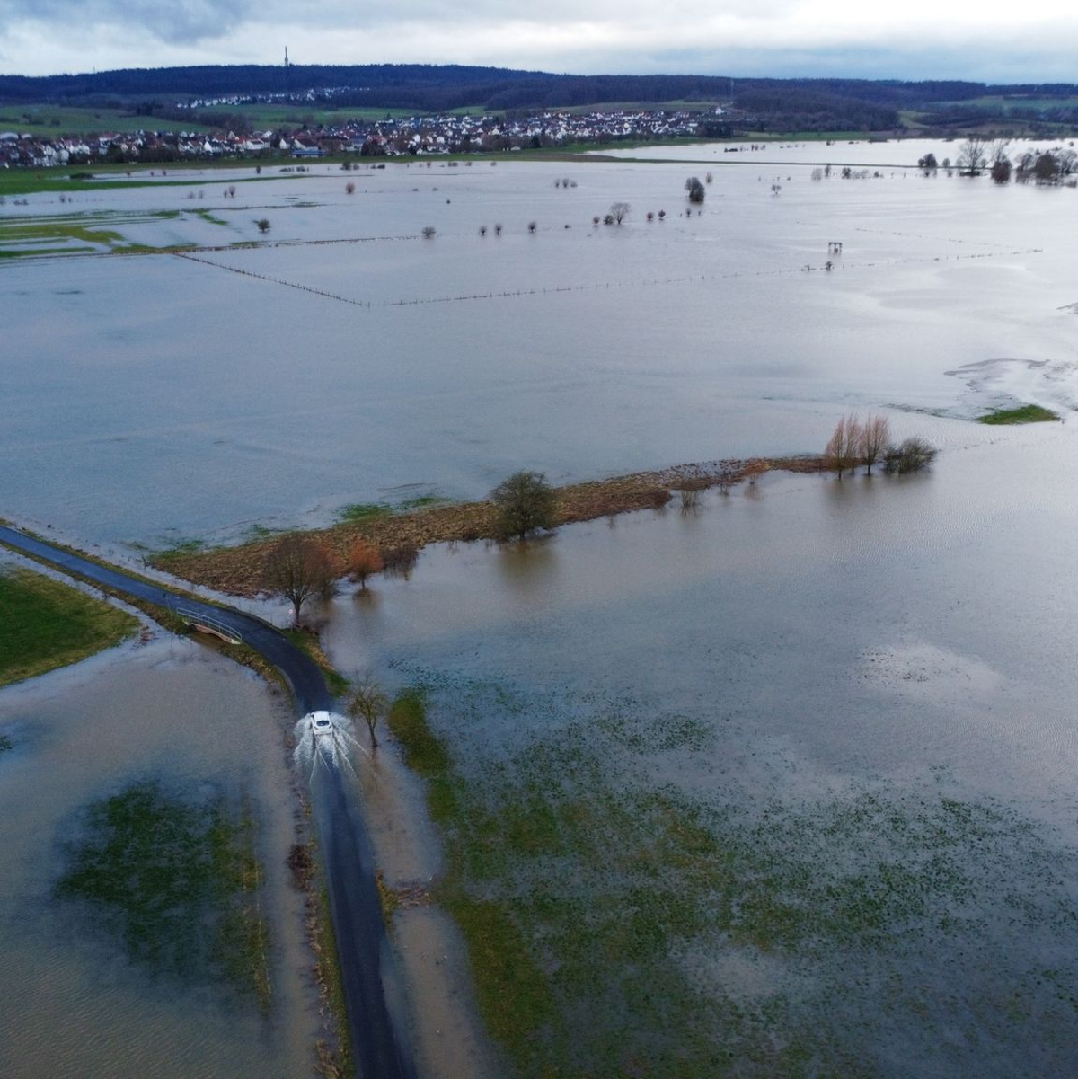 Ein Auto fährt am Rande des aufgestauten Rückhaltebeckens der Ohm. In Hessen ist noch keine Entspannung beim Hochwasser in Sicht. - Foto: Nadine Weigel/dpa