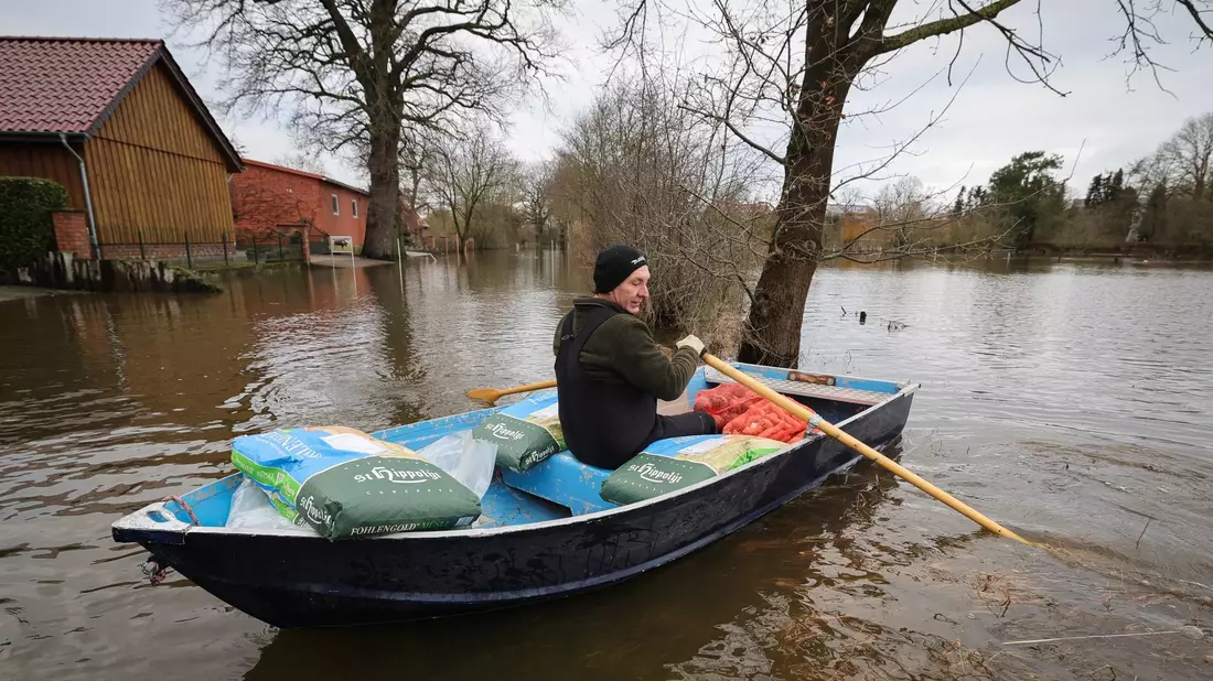 Ein Anwohner bringt mit einem kleinen Ruderboot Futter für seine Tiere über eine überschwemmte Straße in Hagen-Grinden zu seinem Hof. - Bild: Christian Charisius/dpa