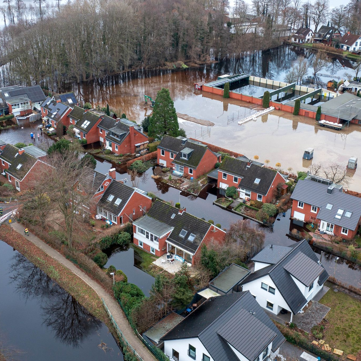Häuser im Hochwassergebiet in der Gemeinde Lilienthal bei Bremen. Weil das überflutete Gebiet zu groß ist, um erfolgreich abzupumpen, errichten Feuerwehrleute eine Barriere mit Sandsäcken. So wird ein Teil der überfluteten Fläche abgetrennt. - Foto: Sina Schuldt/dpa