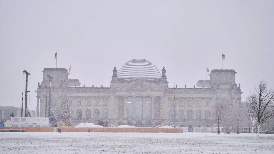 Das Reichstagsgebäude ist mit Schnee bedeckt. - Bild: Annette Riedl/dpa