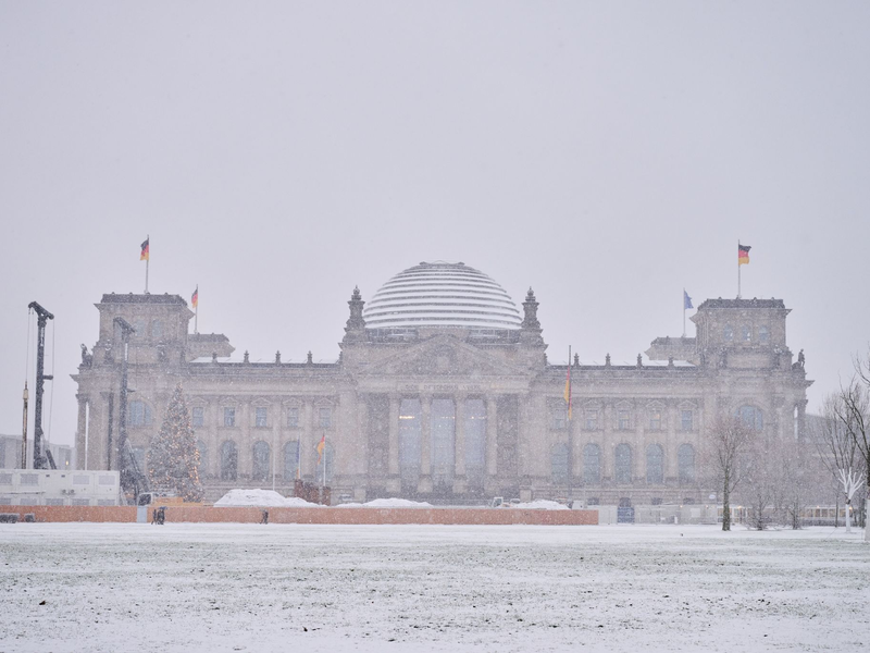 Das Reichstagsgebäude ist mit Schnee bedeckt. - Foto: Annette Riedl/dpa